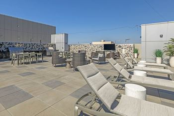 A roof top patio with lounge chairs and tables